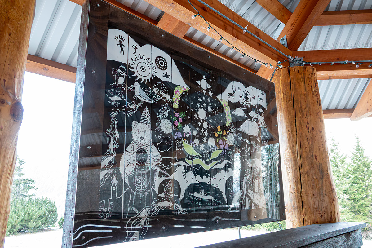 A panel in a wooden structure painted with Indigenous art