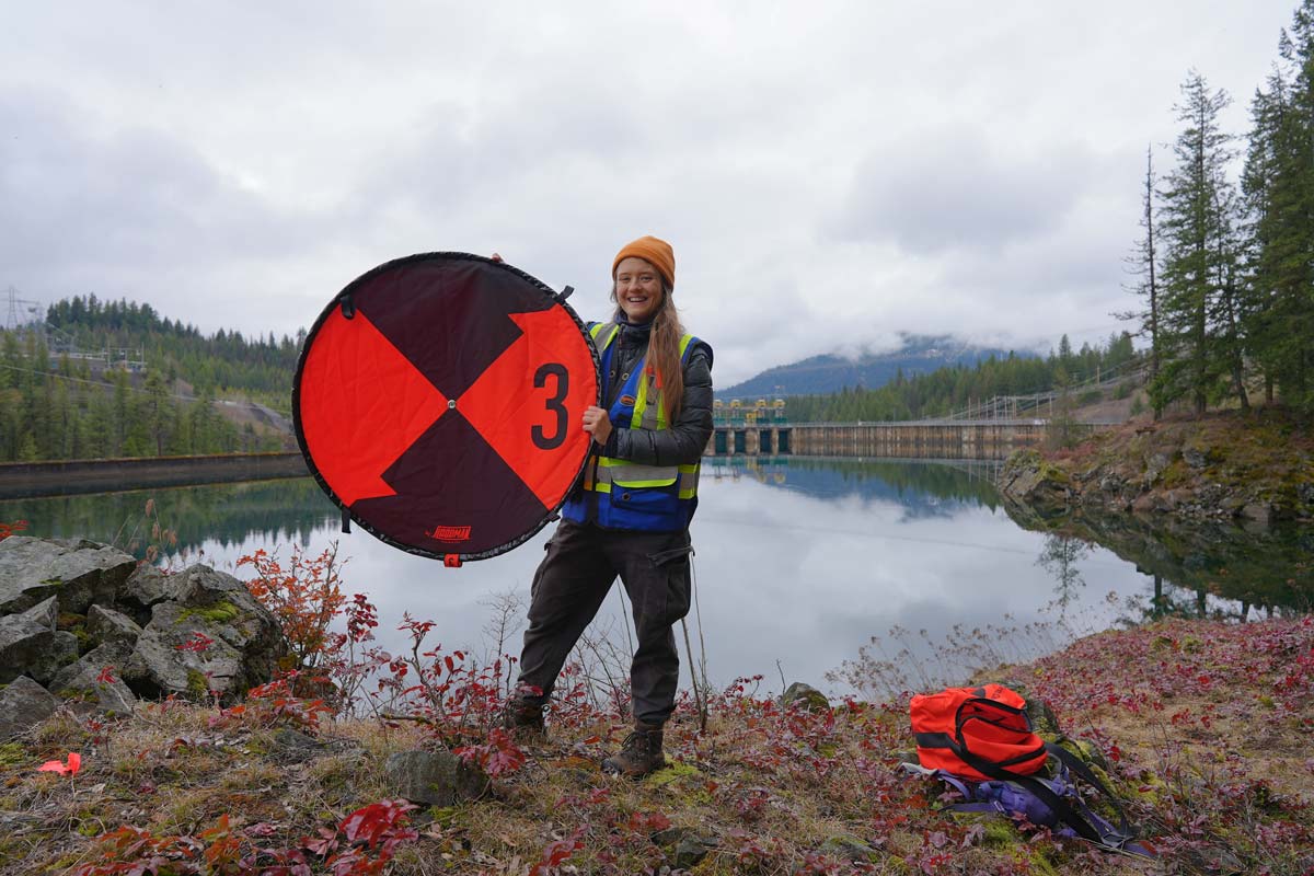 A student intern stands outside holding equipment