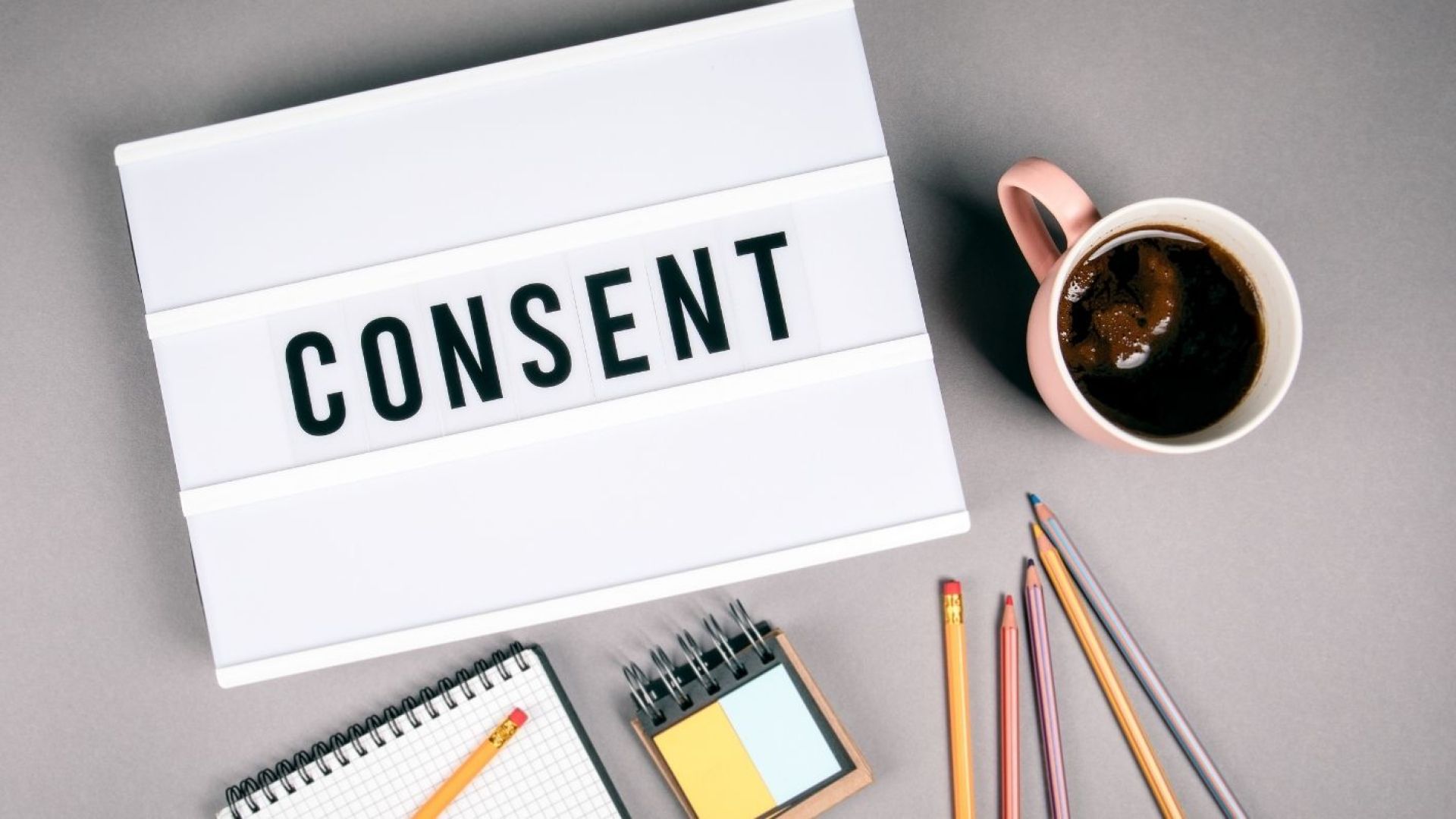 Marquee sign saying consent beside a cup of coffee