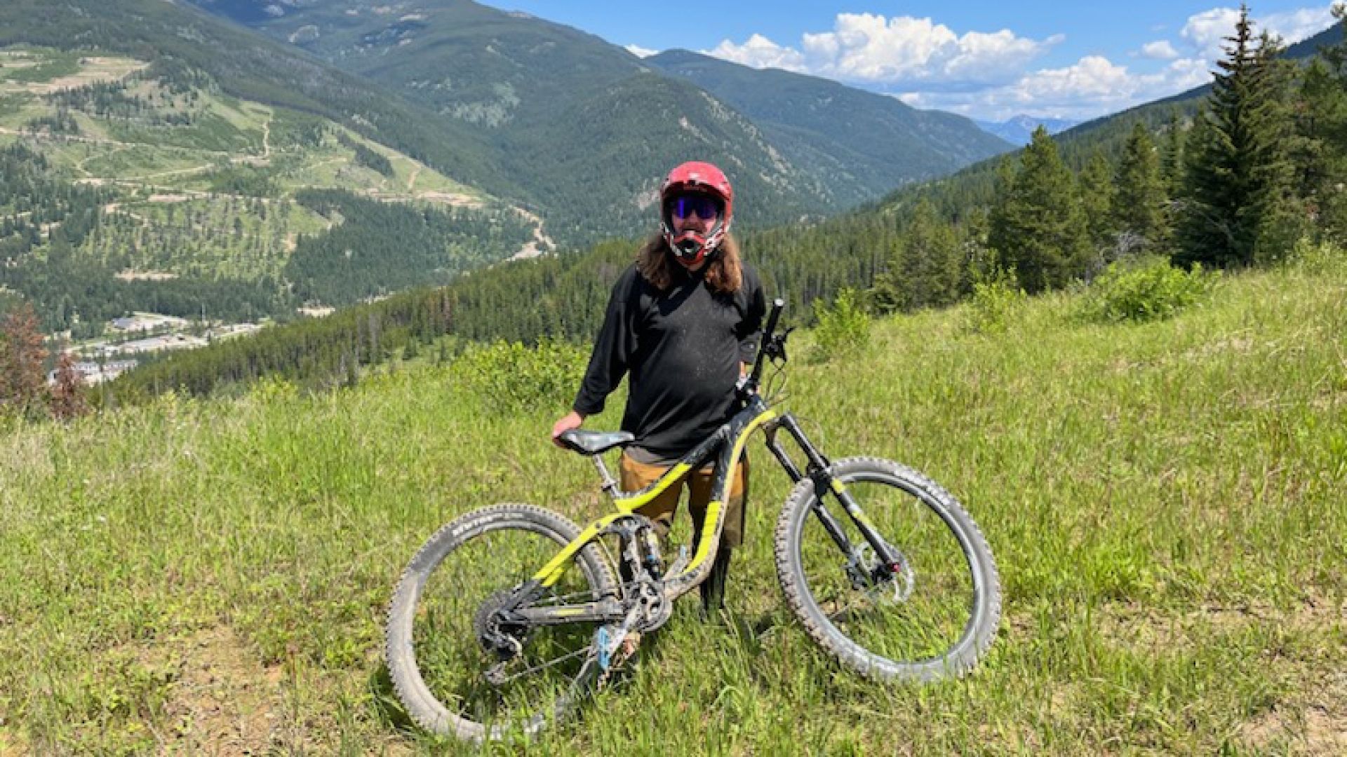 A man stands on a mountain with a mountain bike.