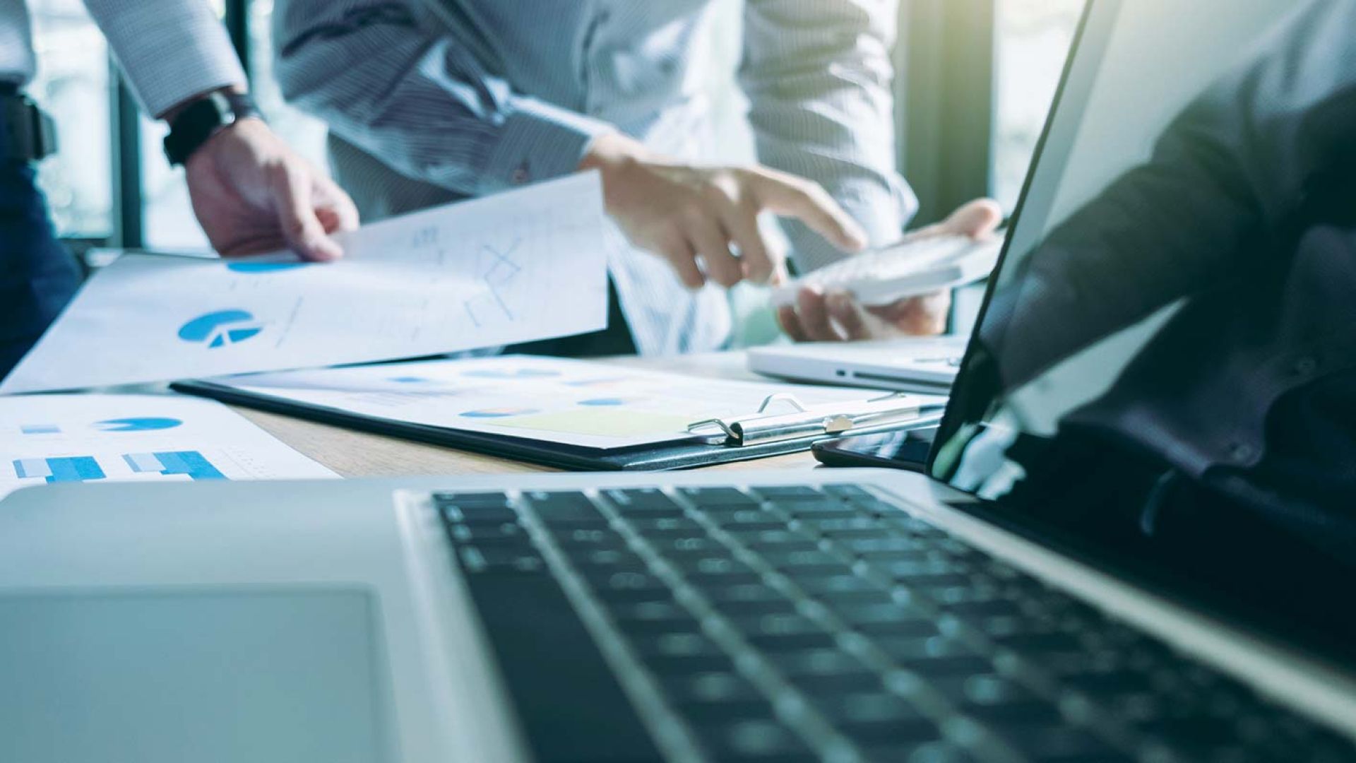 A laptop in the foreground with charts in the background