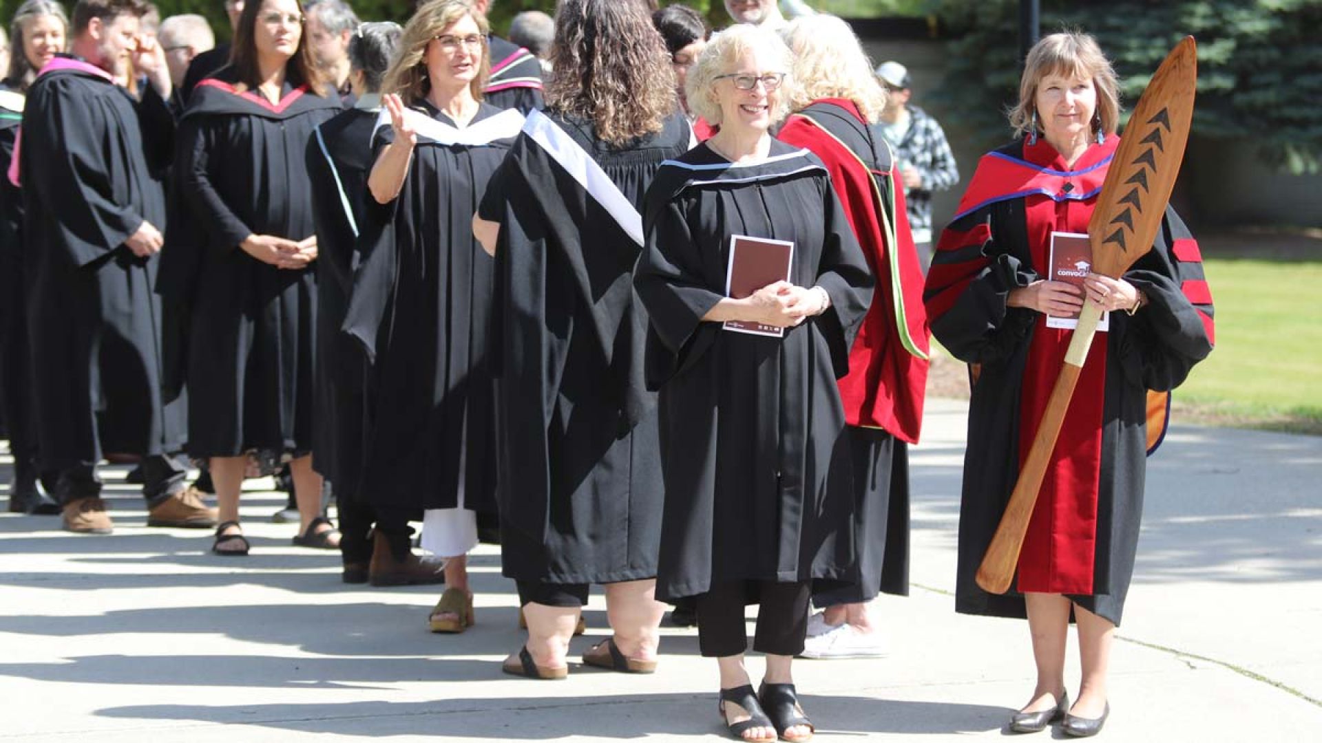 President Maggie Matear and Board Chair Margaret Sutherland stand outside at convocation wearing black robes