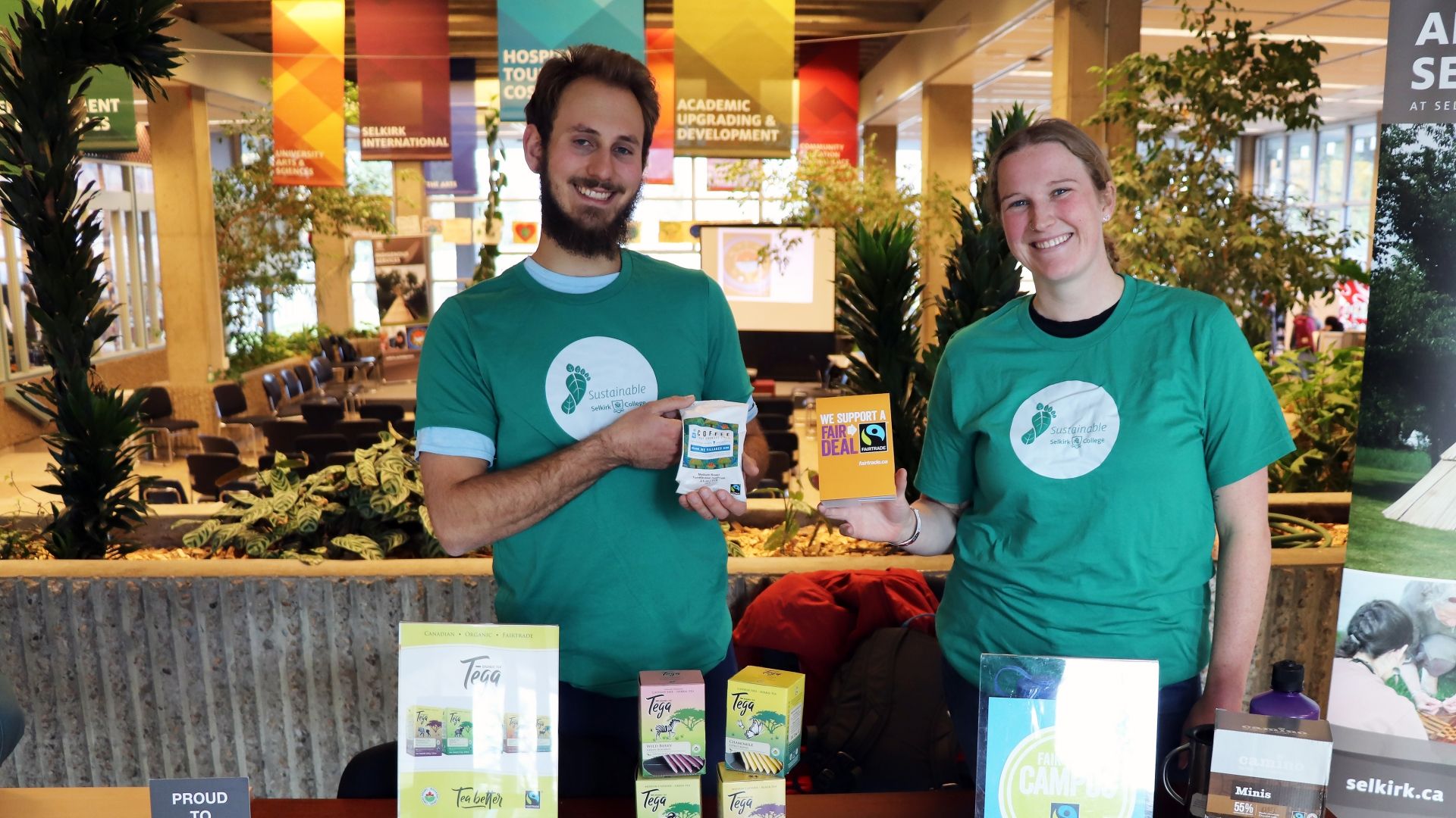 Two students stand at an information table about fair trade