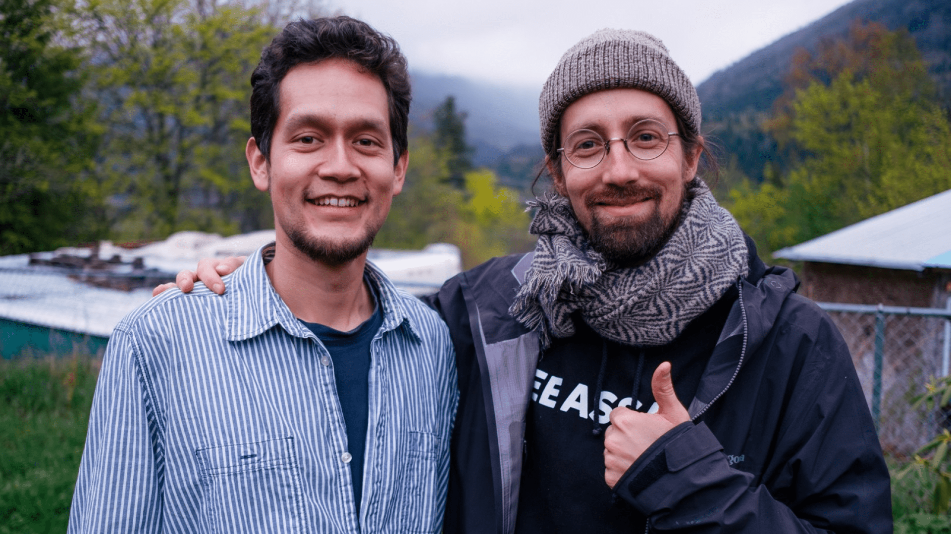 Two men stand together smiling