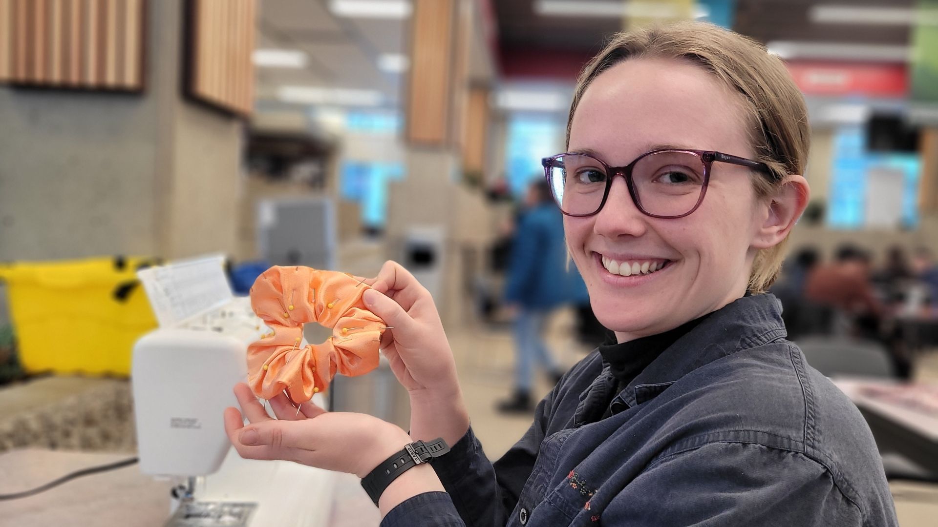 A smiling person holds up a scrunchie