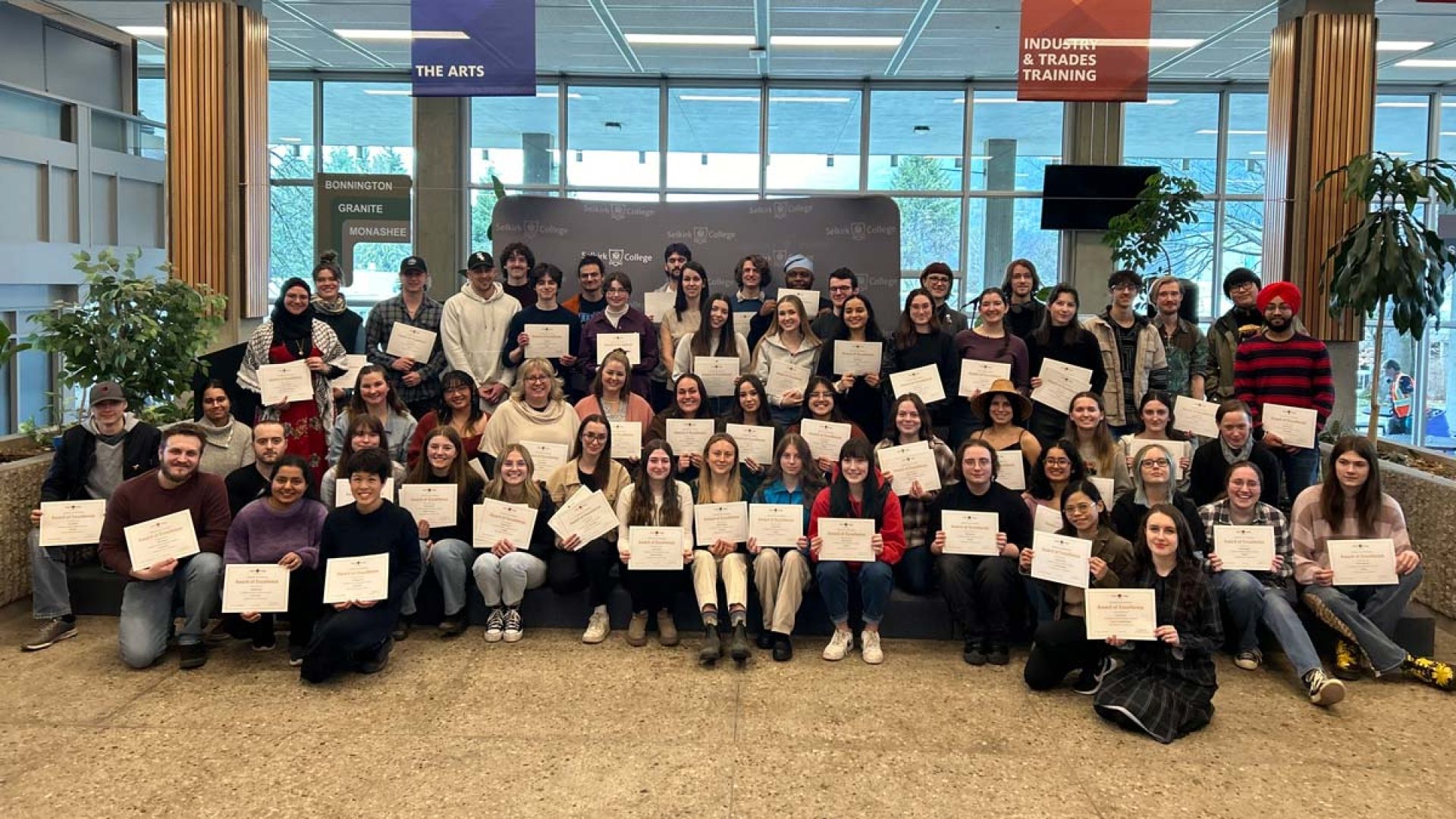 A group of students hold up certificates