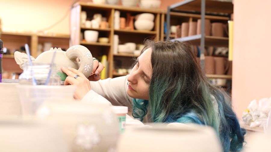 Student painting clay tea pot