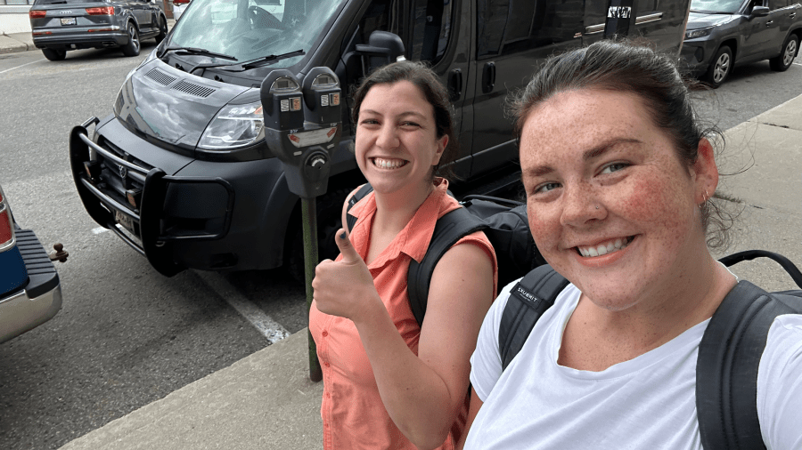 Two students wearing backpacks smile