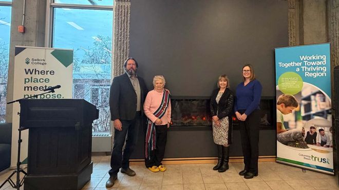 Representatives from Selkirk College and the Columbia Basin Trust stand in front of a new fireplace