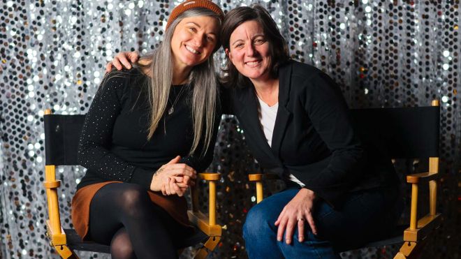 Amy and Carla sit smiling in directors chairs