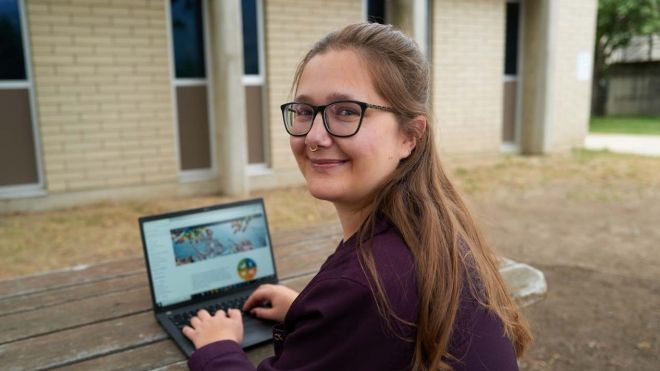 Leeza sits outside with her laptop