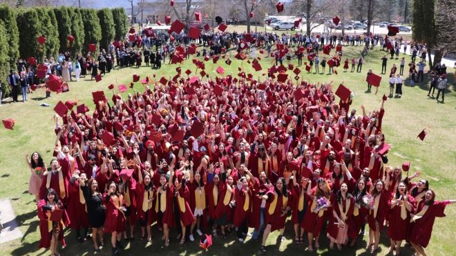 A group of graduates stand together in red robes after Convocation