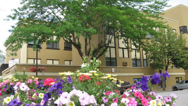Selkirk College's Trail Campus building with pink and purple flowers