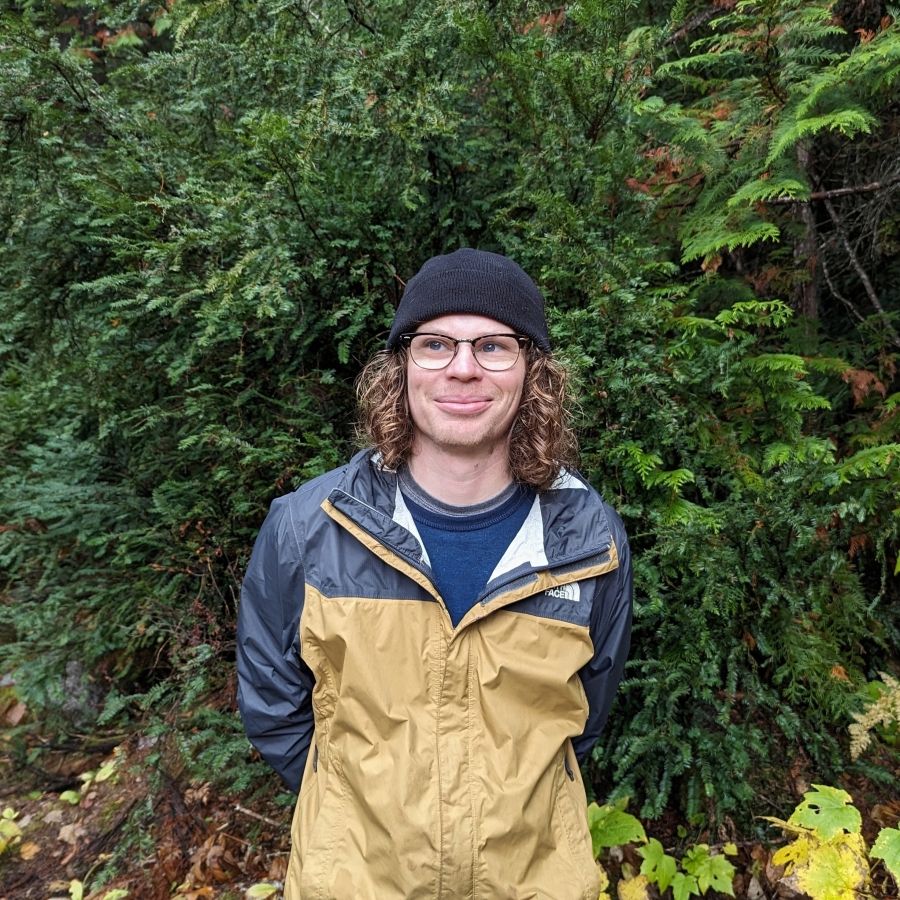 A man wearing a toque standing in a forest