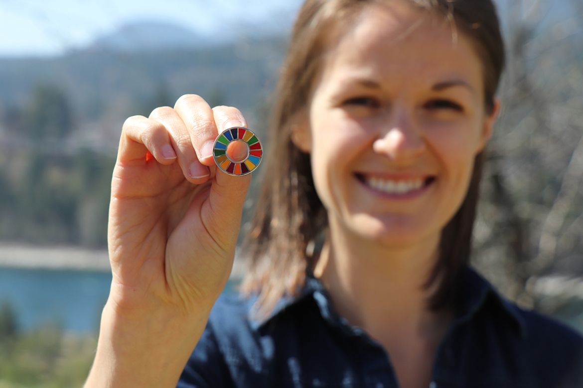 Laura Nessman holding up a SDG enamel pin