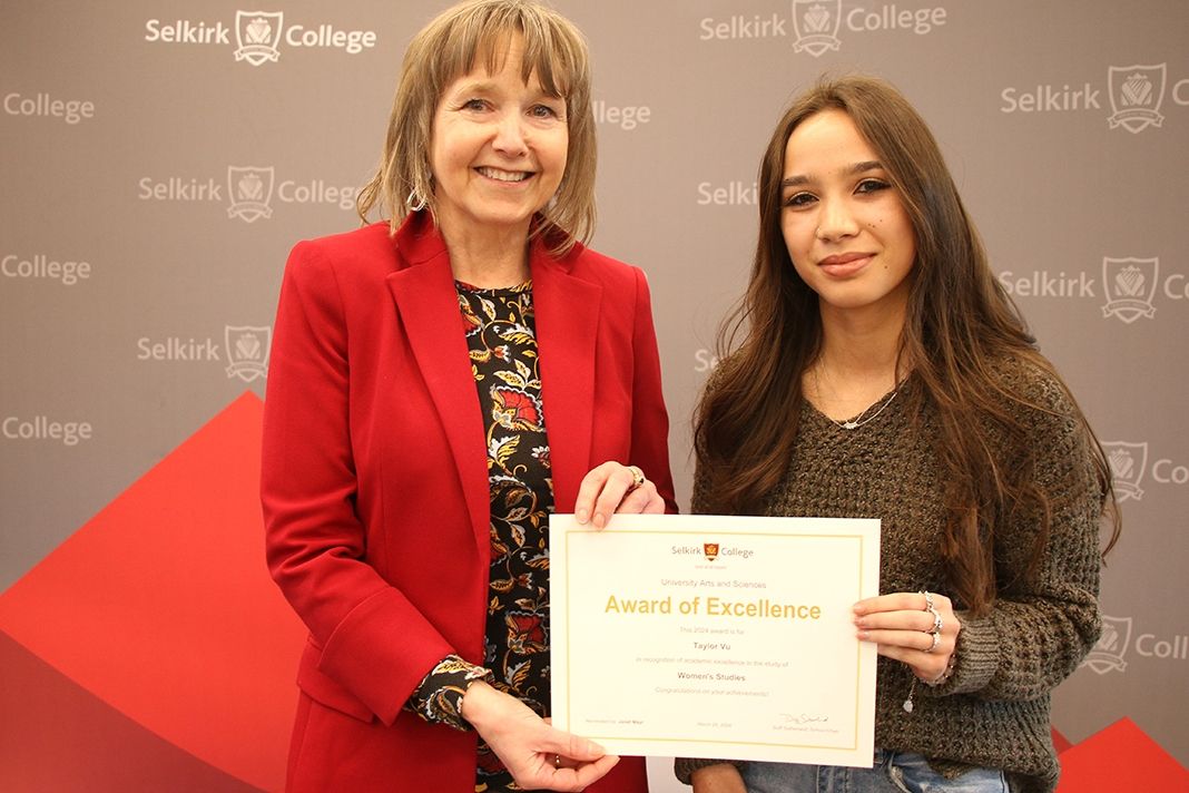 Two women stand holding a diploma
