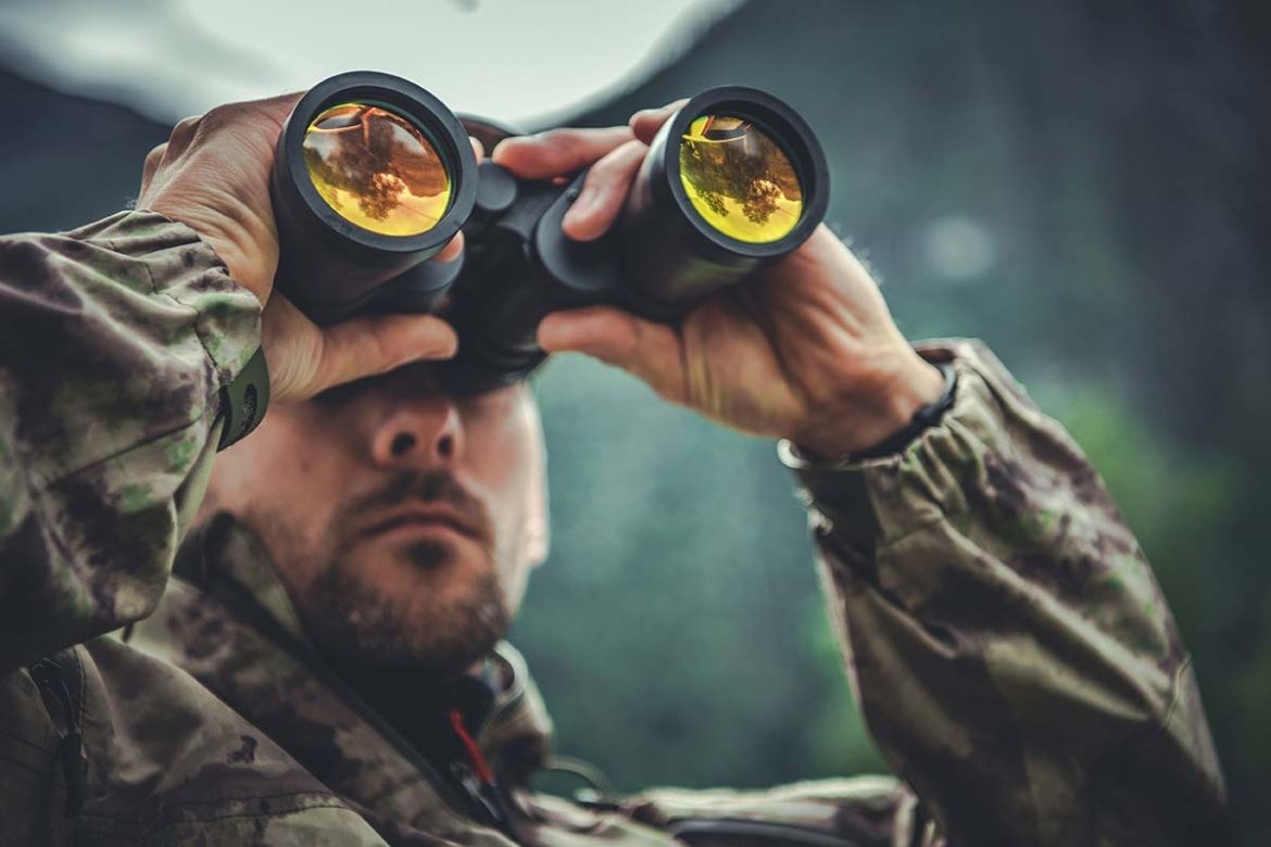 A hunter looks through binoculars