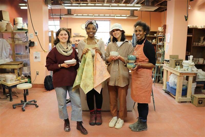 A group of students stand holding textiles