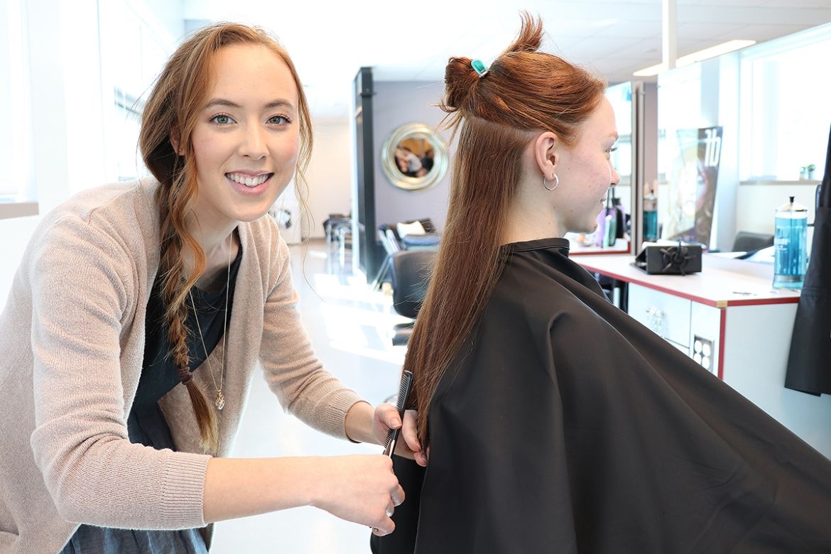 Hairstylist student cutting client's hair