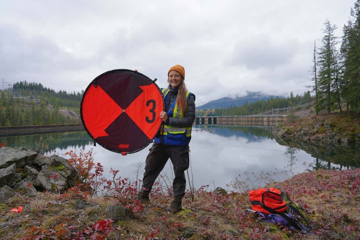 A student intern stands outside holding equipment