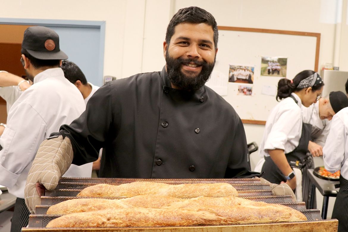 Professional Cook student holding a fresh pan of bread