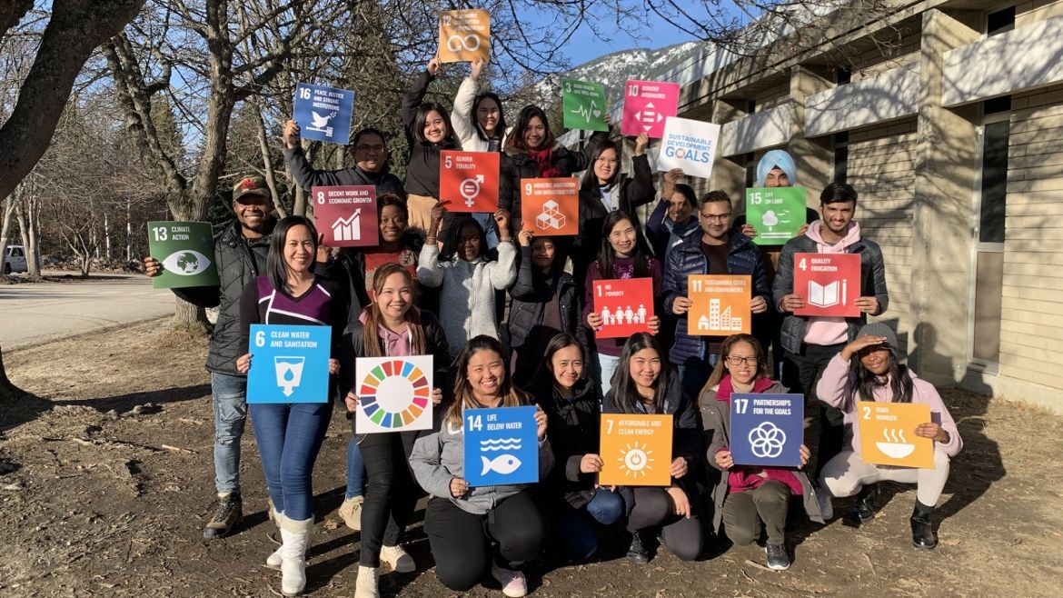 A group of students hold up signs of the Sustainable Development Goals
