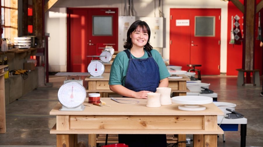 Ceramics graduate Alice Gibson stands in a pottery studio