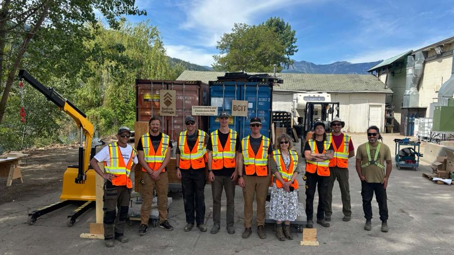 A group of people wearing hi-vis vests stand outiside