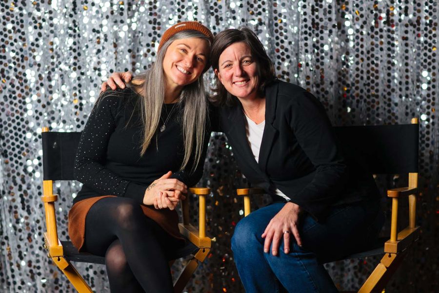 Amy and Carla sit smiling in directors chairs