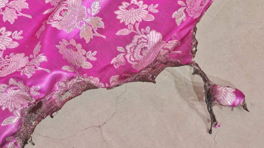 A bright pink textile with burned edges