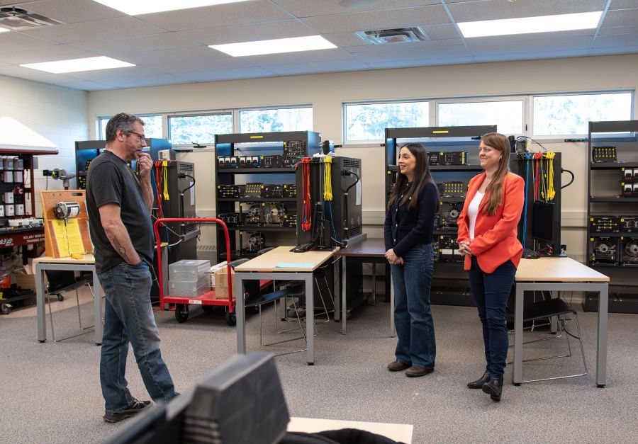 Three people stand in an electrical lab