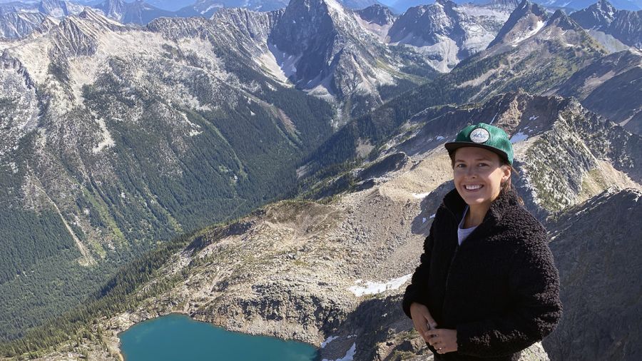 Holli Norberg stands in front of a mountain range