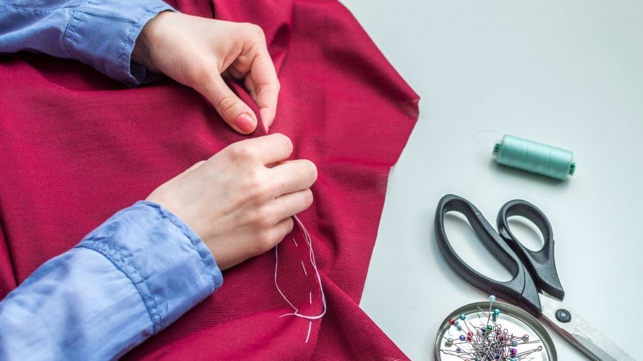 Hands sewing a piece of red fabric