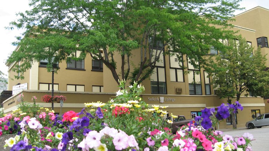 Selkirk College's Trail Campus building with pink and purple flowers