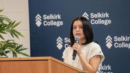 A bursary recipient stands at a podium speaking into a microphone