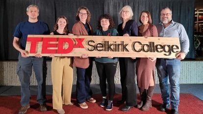 TEDx speaker group from 2023 holding sign