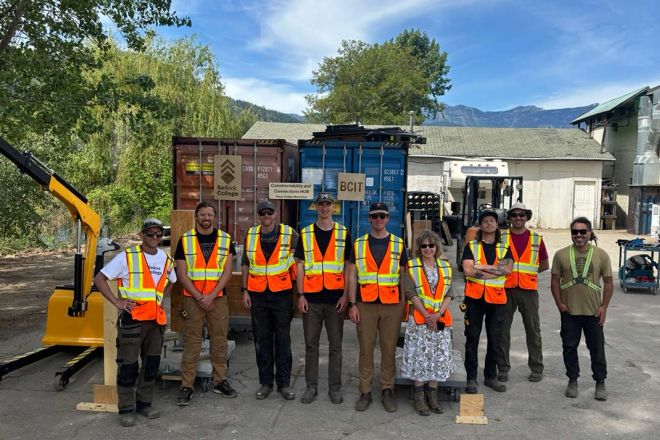 A group of people wearing hi-vis vests stand outiside