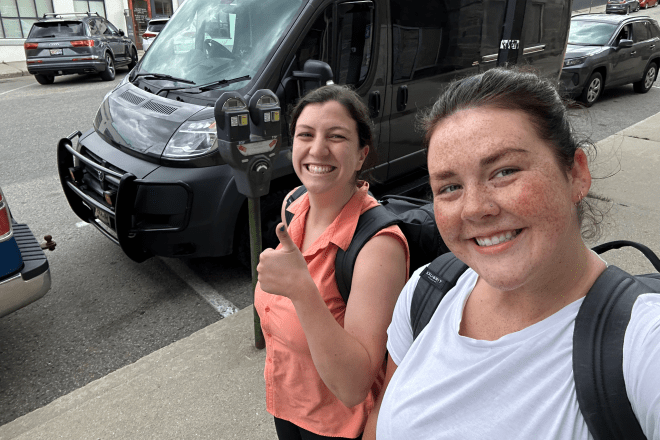 Two students wearing backpacks smile