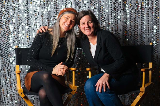 Amy and Carla sit smiling in directors chairs