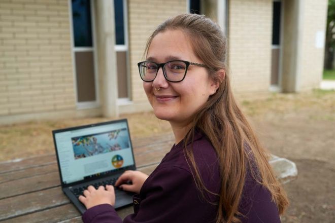 Leeza sits outside with her laptop
