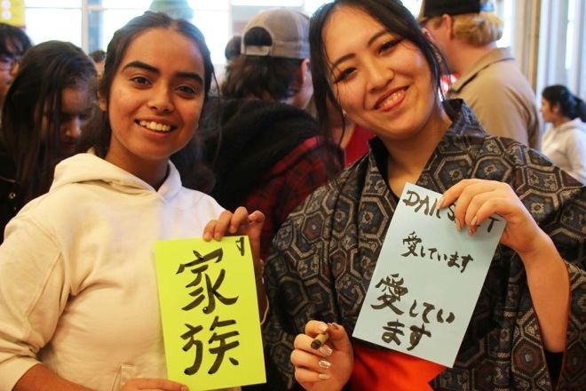 Students at the 2023 Interculturual Fair hold up Japanese writing