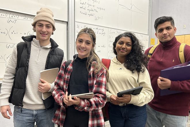 A group of four students stand smiling