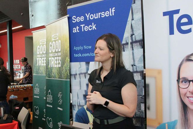 A woman stands at a Teck booth at a career fair